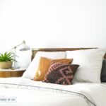 Modern Eclectic Mid-Century Bedroom with white duvet , West Elm nightstand, blue and white rug and plants