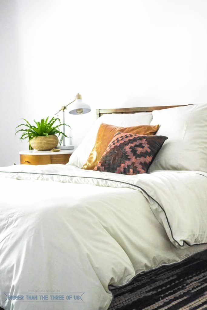 Modern Eclectic Mid-Century Bedroom with white duvet , West Elm nightstand, blue and white rug and plants