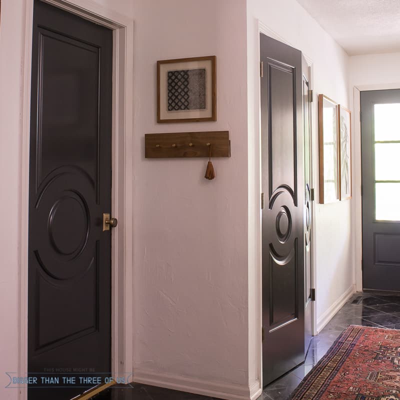 Entryway with dark doors, marble flooring, white walls and black and white accents