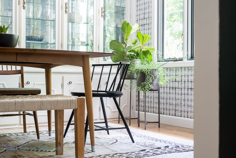 Mid-Century Dining Room with black chairs, tall planters and vintage rug