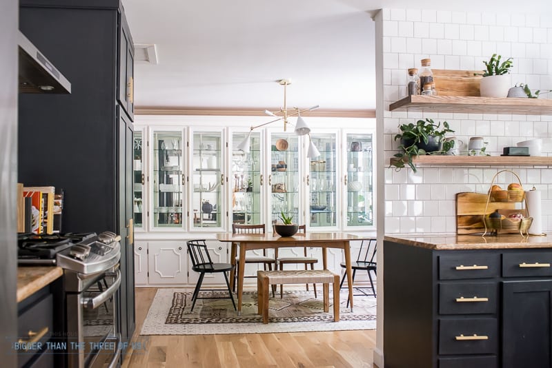 Navy and White kitchen with open shelving open to the dining room with mid-century furniture