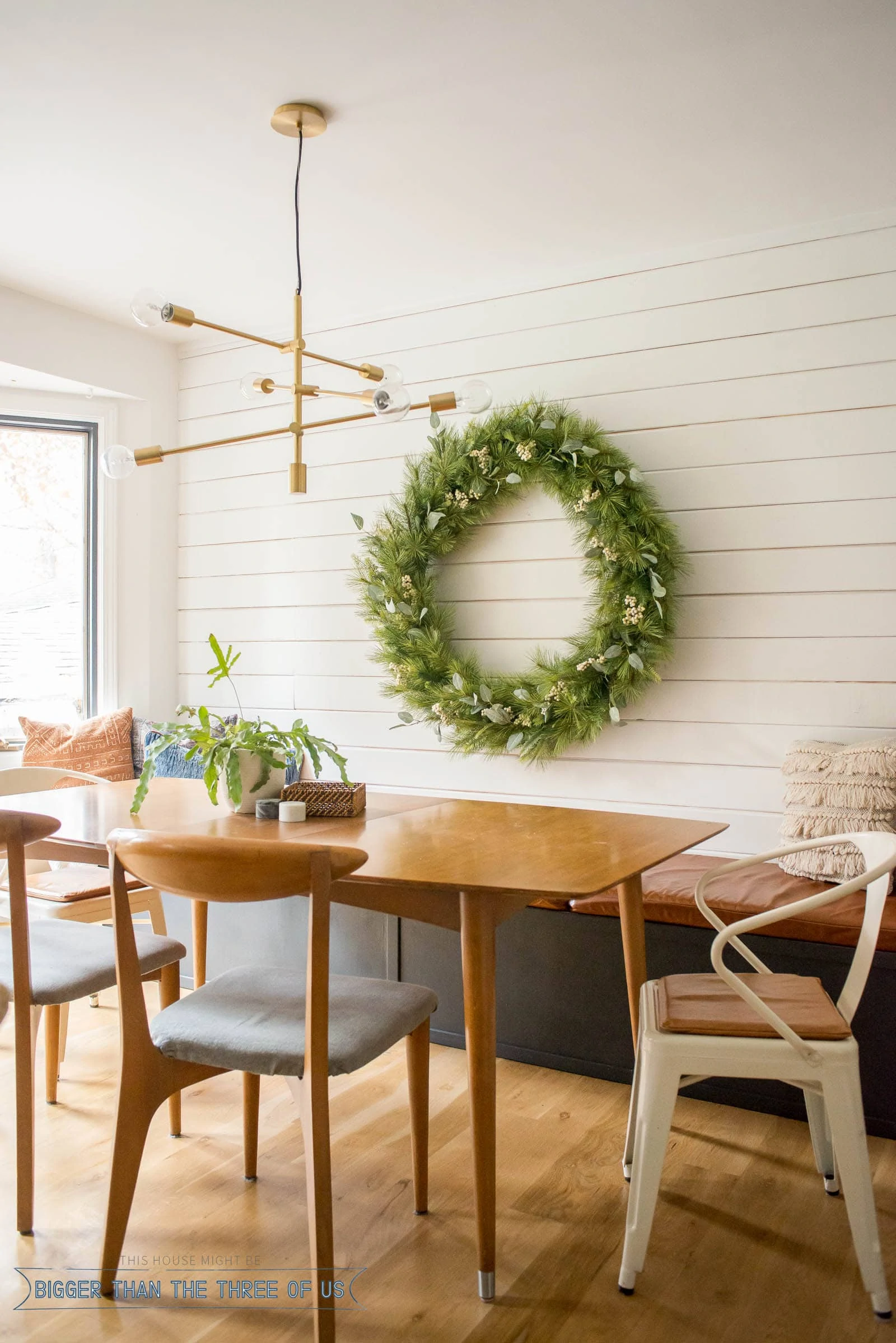 Christmas Decor in Dining room showing an oversized wreath on a shiplap wall with a built-in bench with leather cushion.