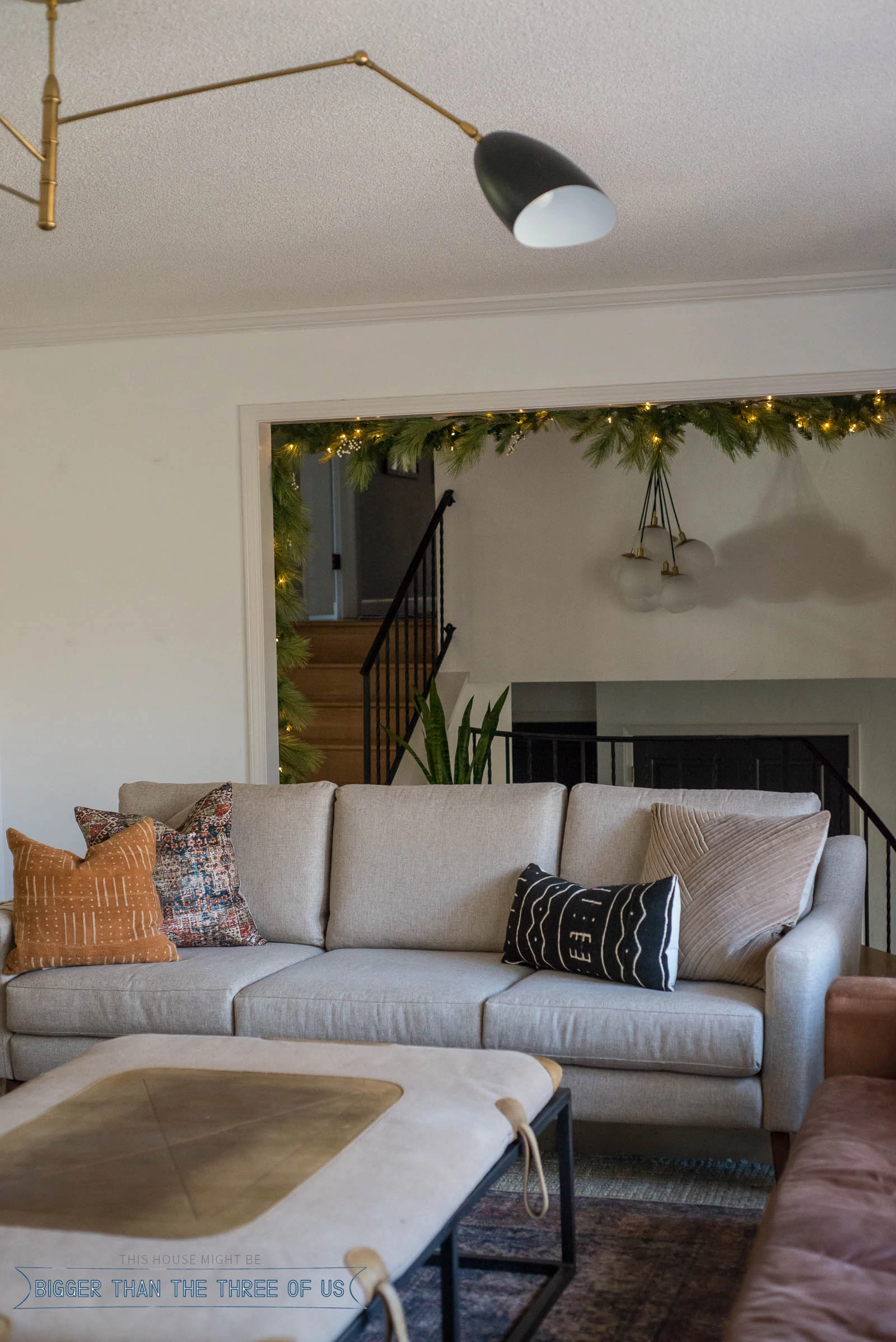 Gray couch in living room with garland strung over doorway behind it. 