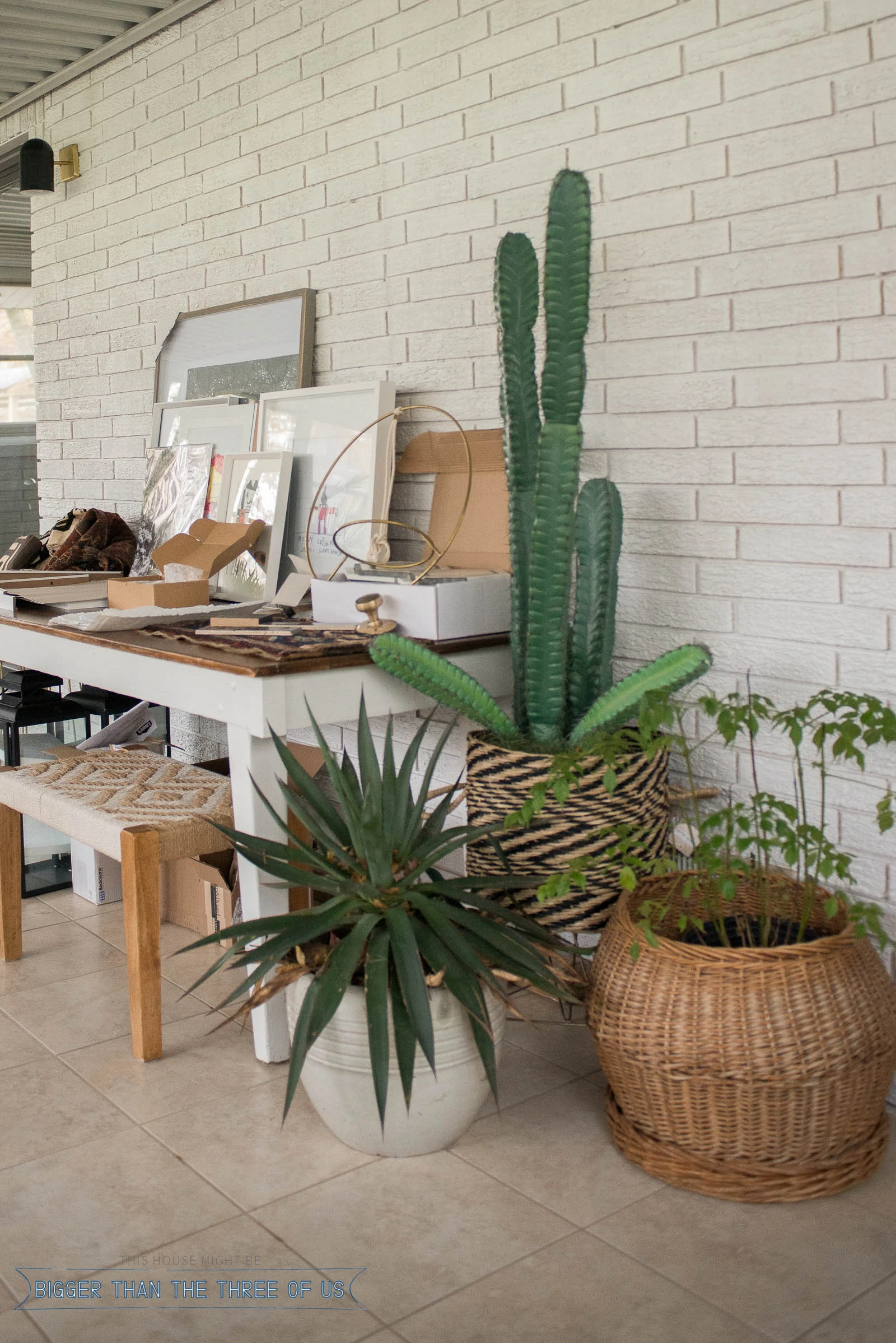 A table filled with project supplies and plants on the floor next to it. 