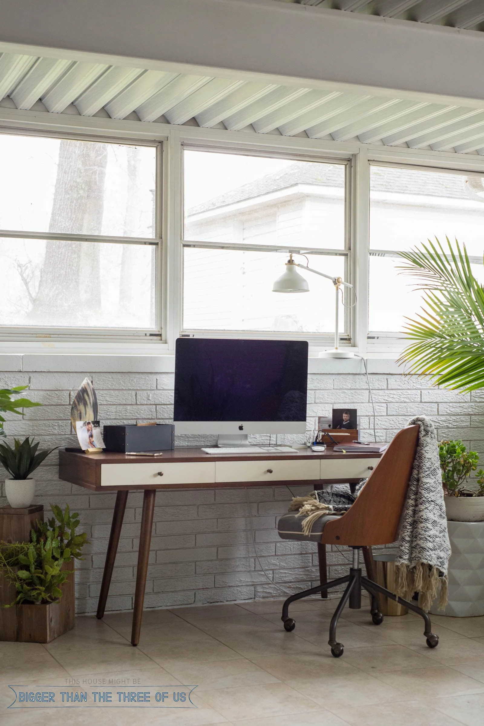 Mid-Century Modern walnut desk in sunroom with plants