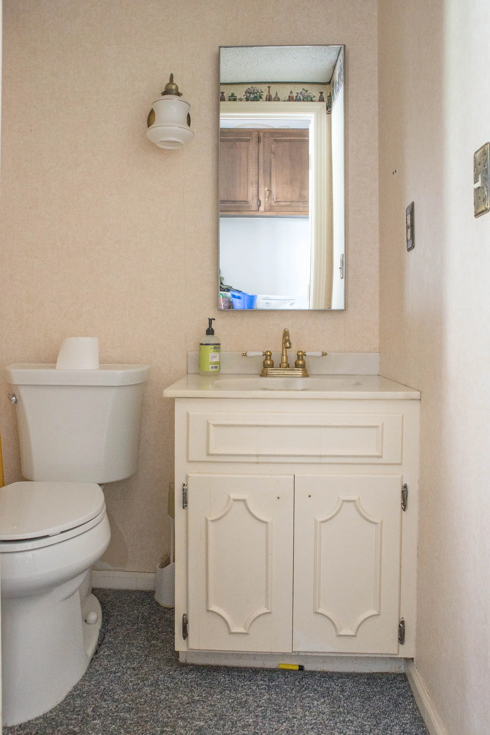 Before photo of powder bathroom with cream vanity and carpet