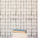 A stack of books in front of wallpaper