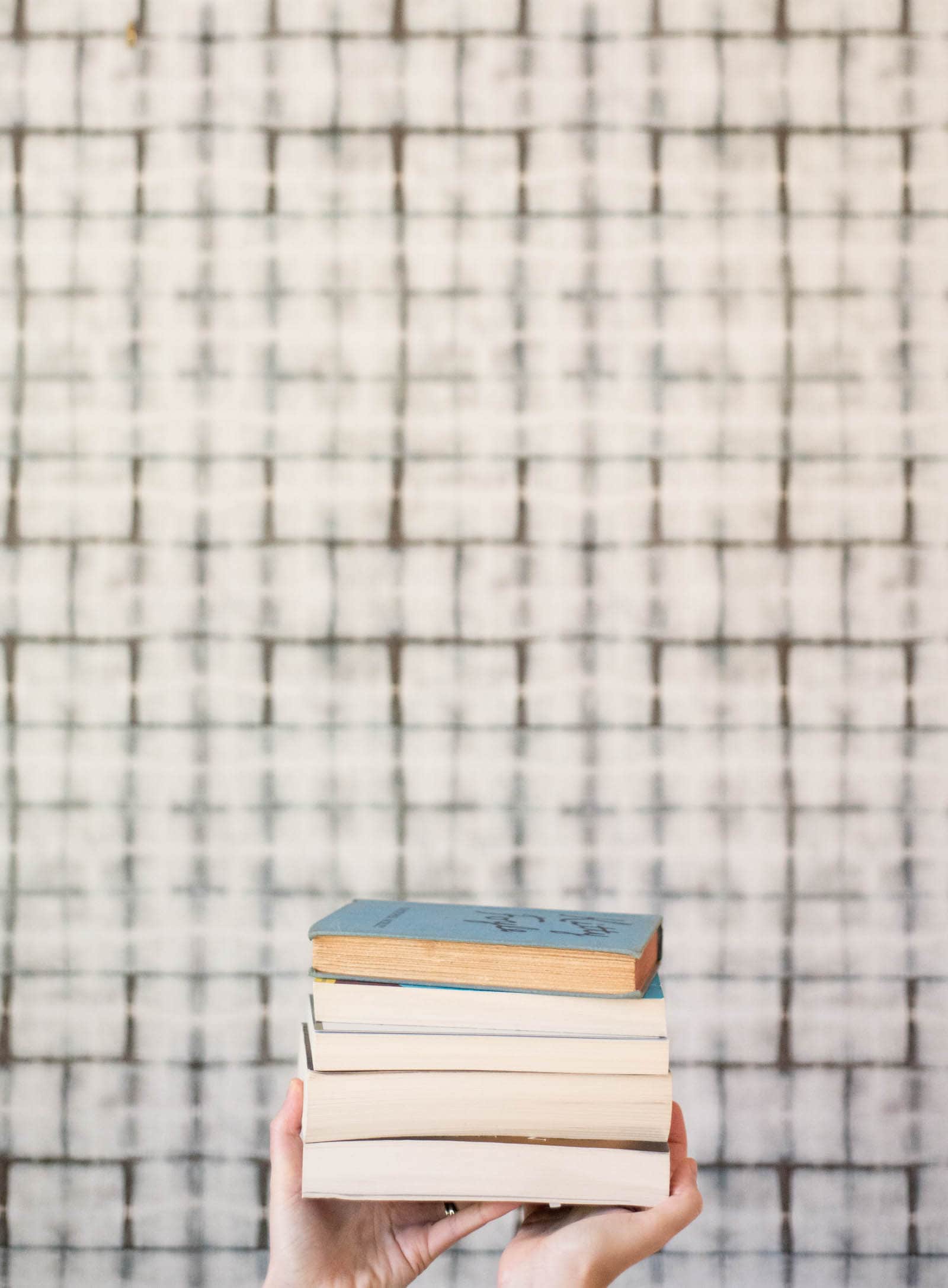 A stack of books in front of wallpaper