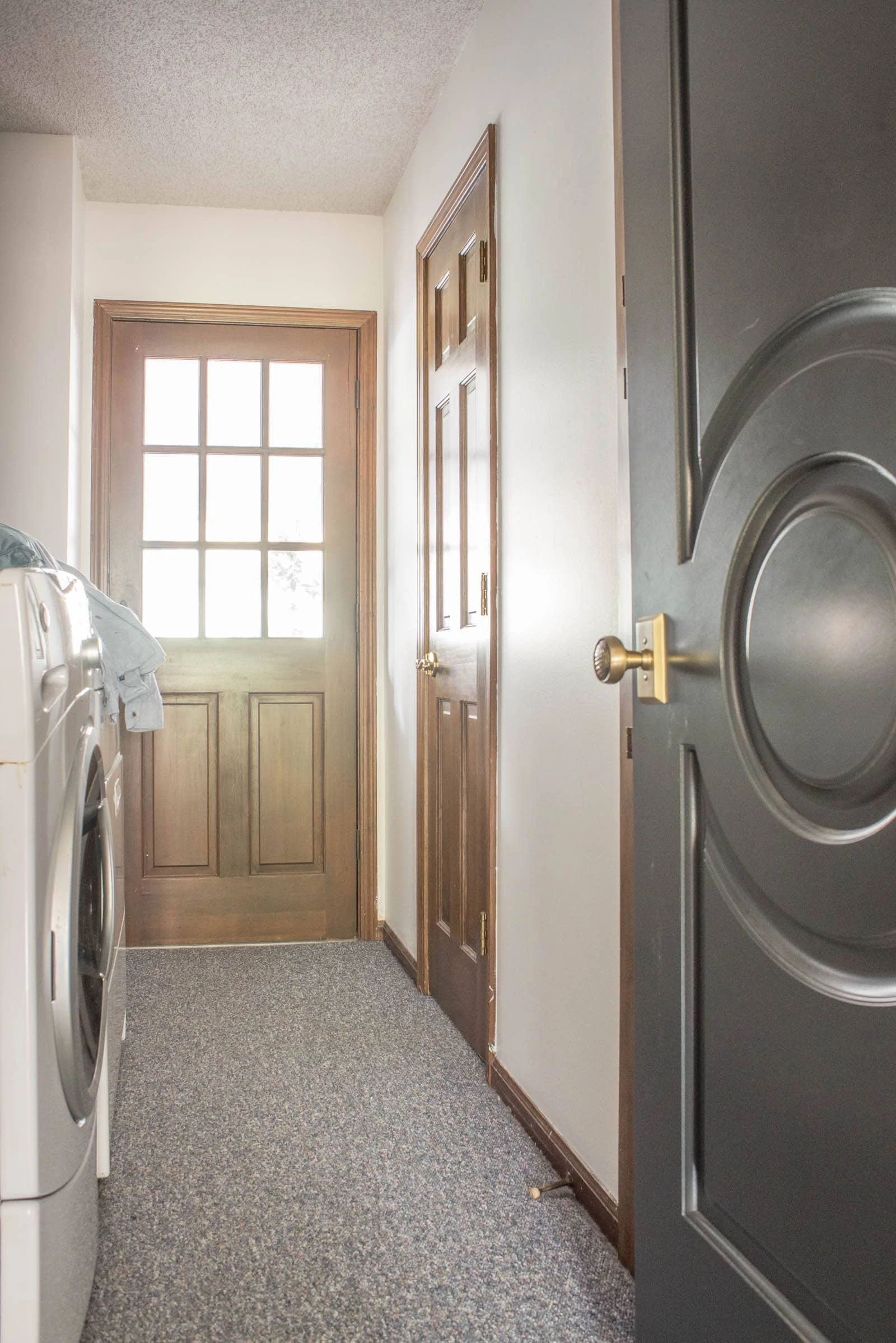 Washer and dryer in a long hallway with a powder bathroom off of it