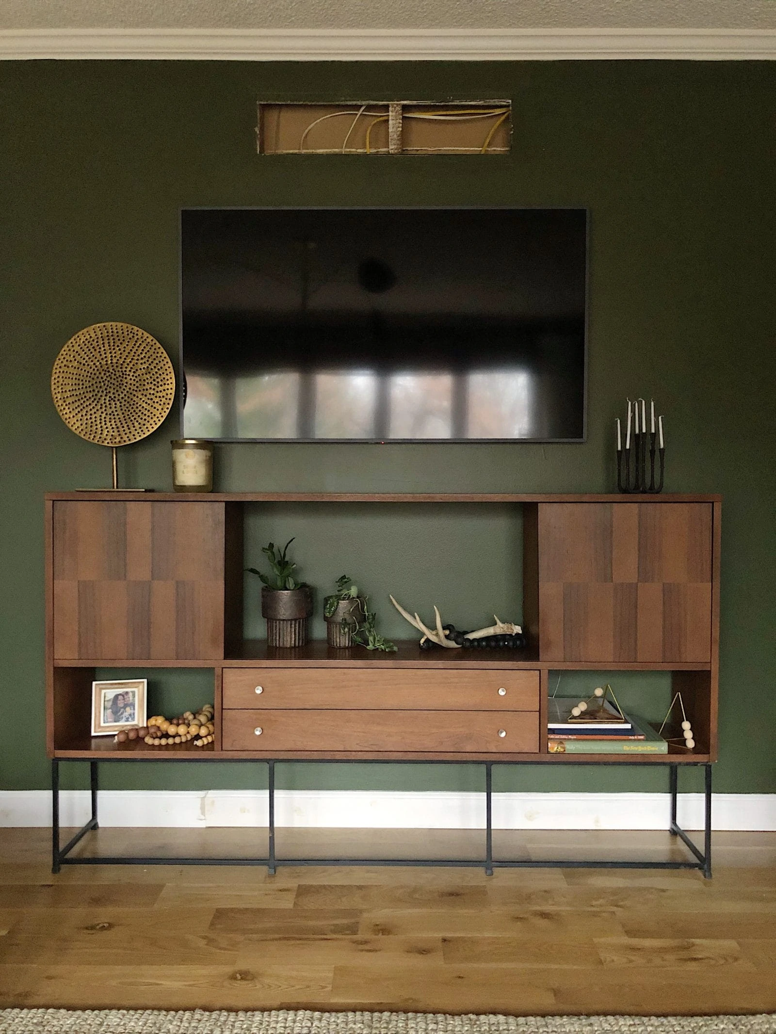 Mid Century Buffet as TV Console in front of a green wall and what it means to show hospitality. 