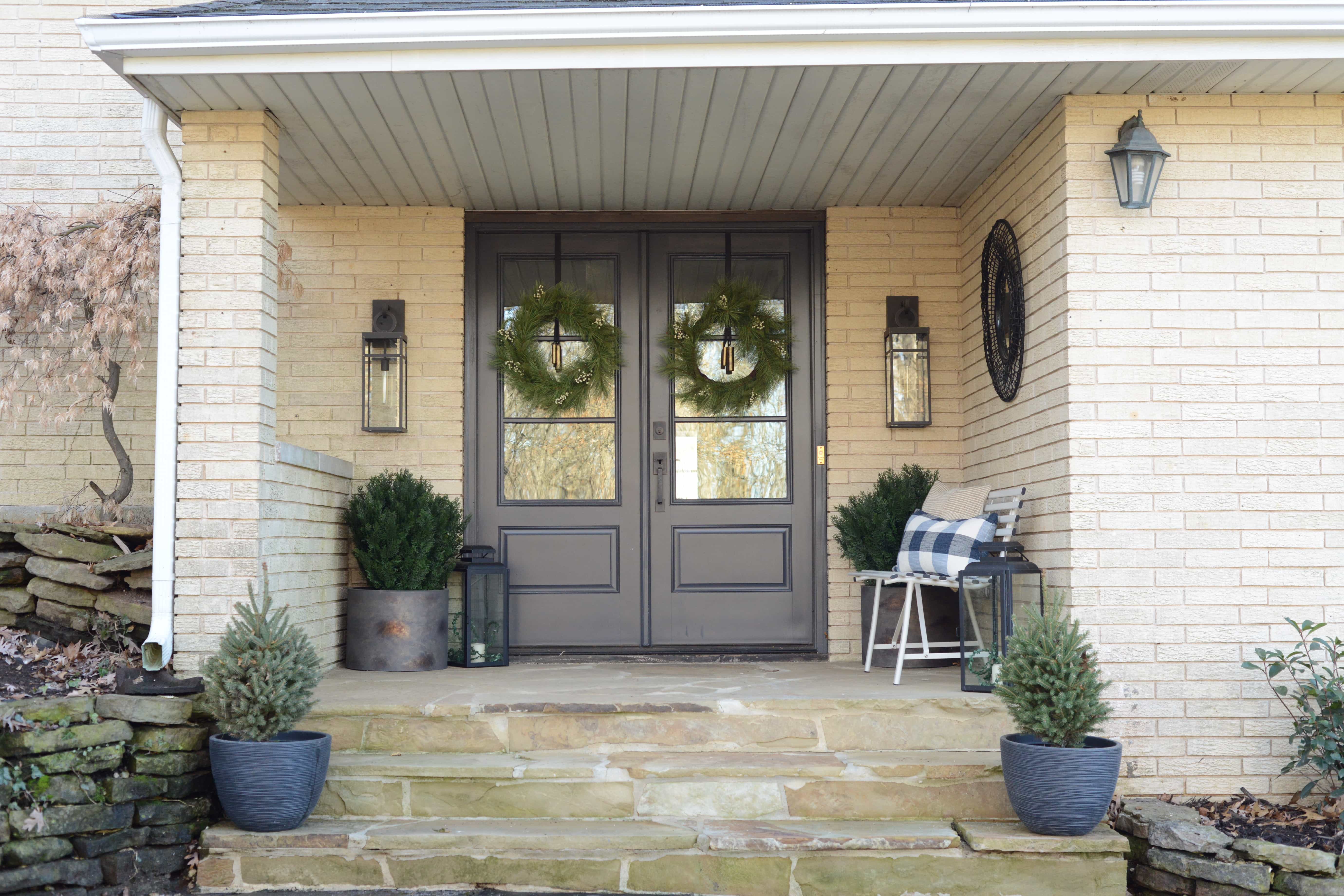 Front porch view with stone floor, black front doors and wreaths