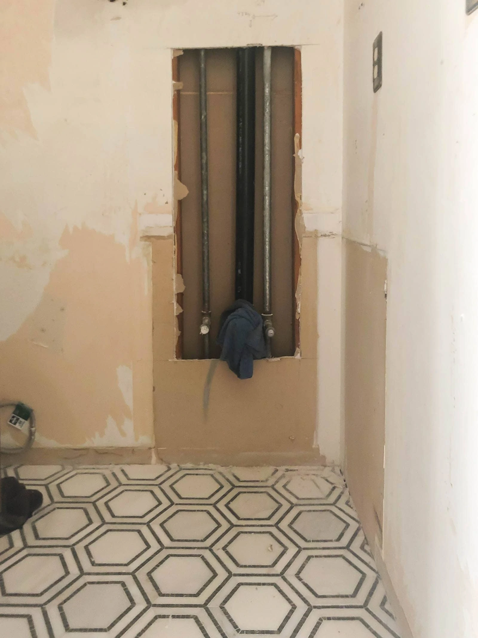 Drywall cutout in bathroom showing plumbing lines