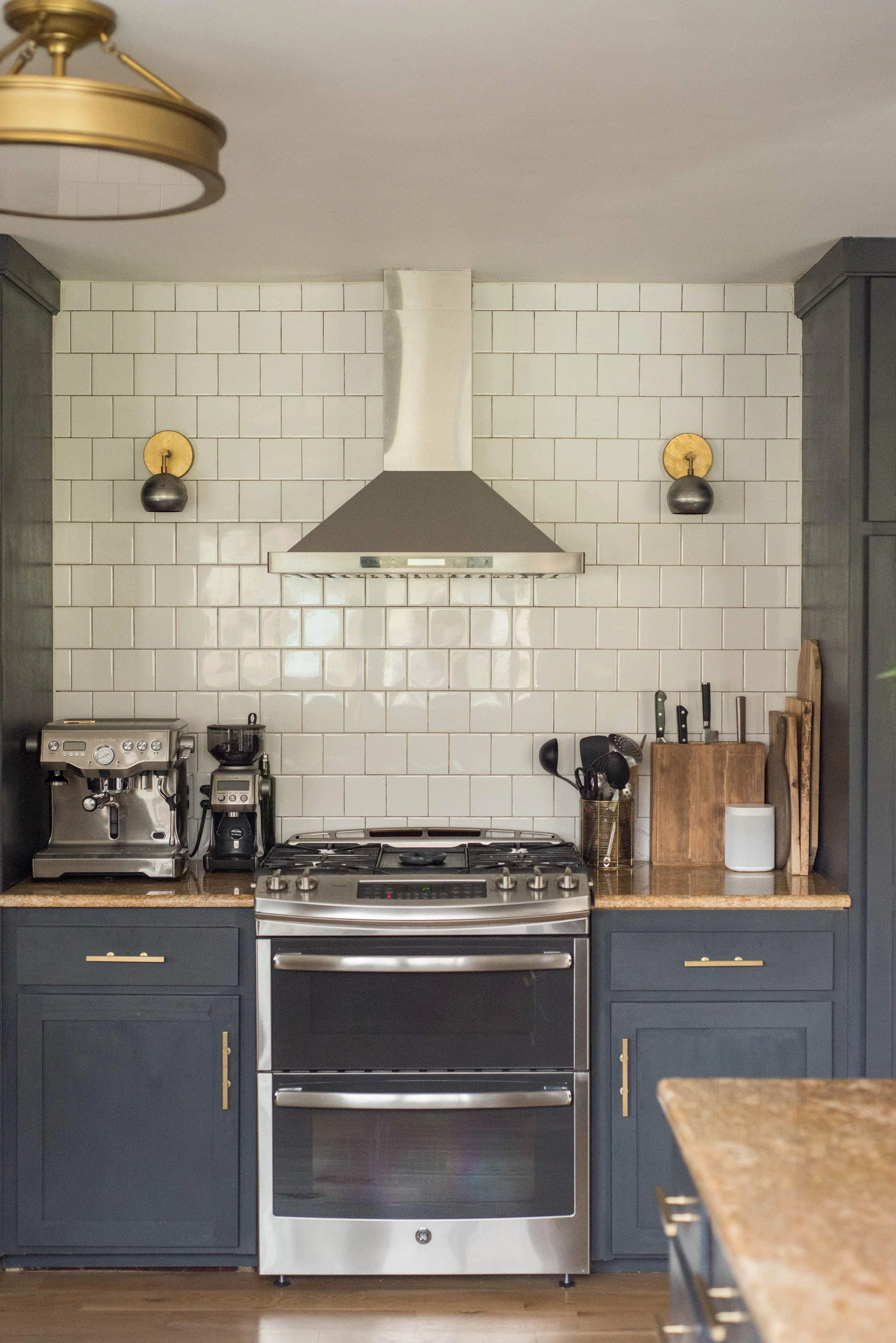 Kitchen space with oven, sconces and white tile. 