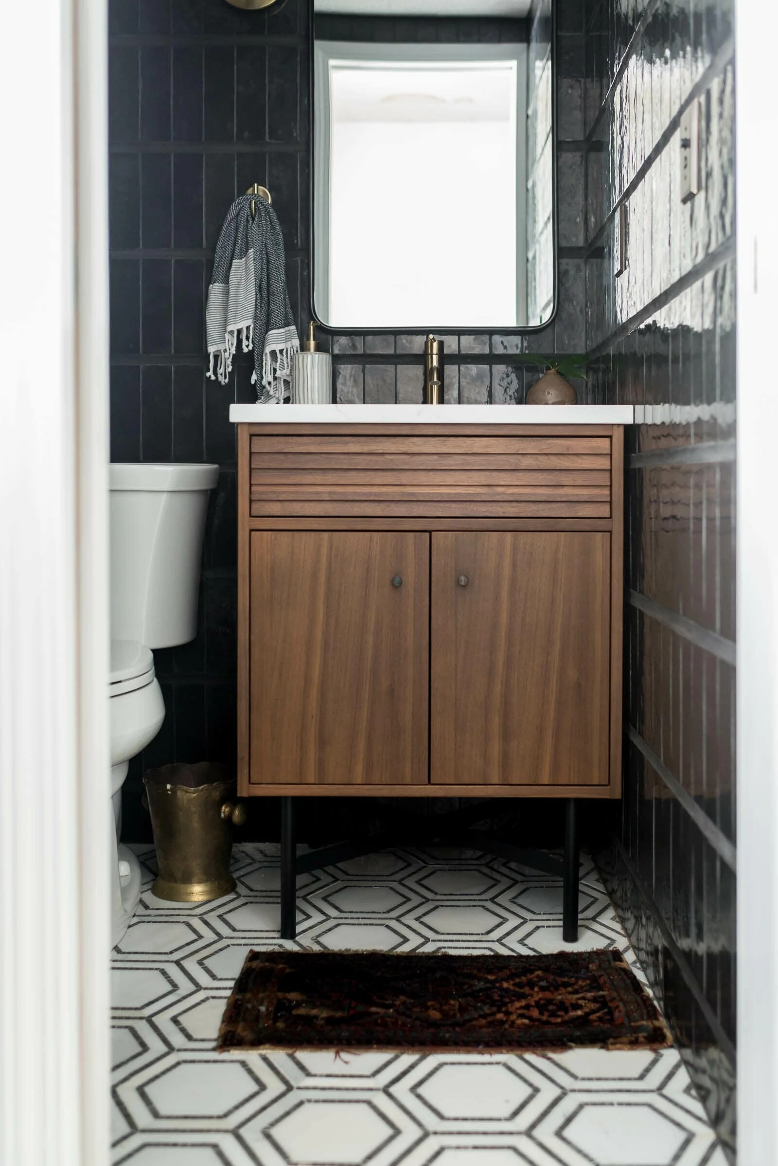 Modern powder bathroom with black tile and walnut vanity