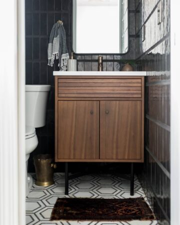 Modern powder bathroom with black tile and walnut vanity