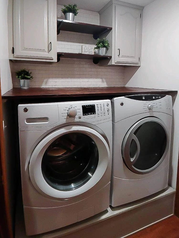 A newbie DIYers transforms the laundry room with peel and stick tile, DIY pedestal for washer and dryer and more. 