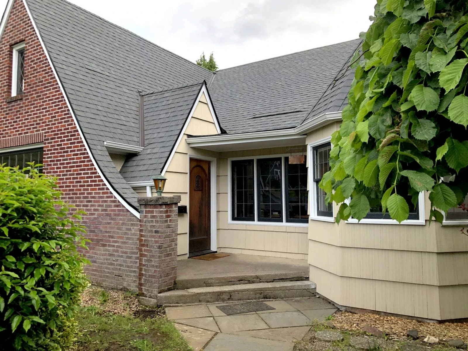 A recently painted cream siding house with red brick.