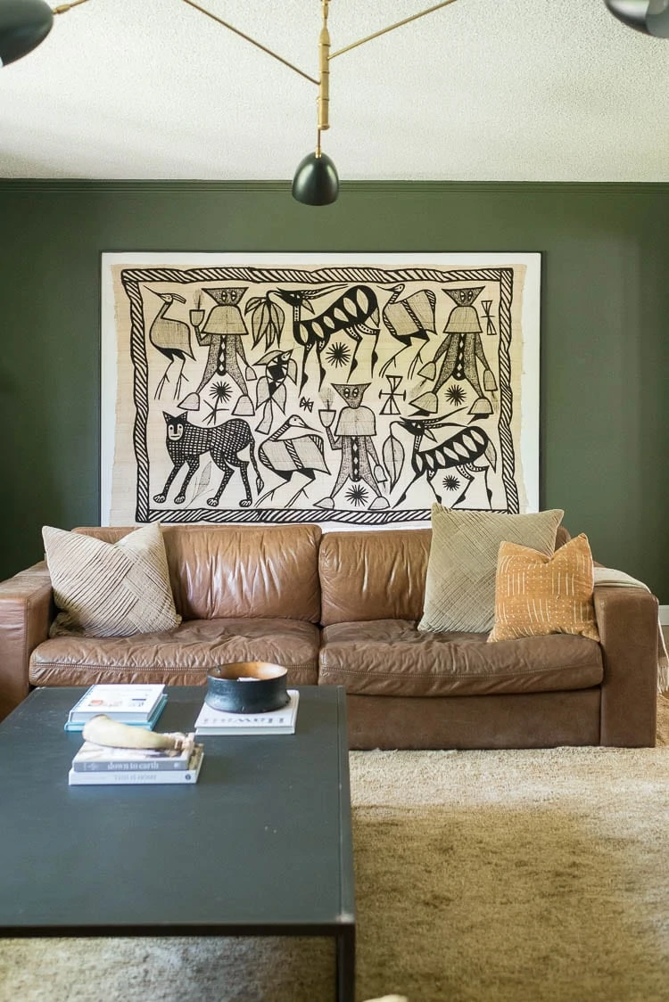 green living room walls with Korhogo Cloth behind couch