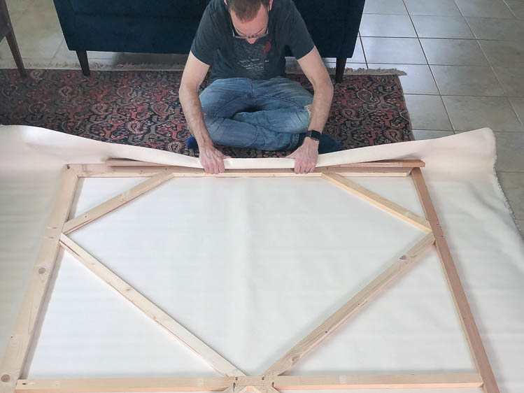 Man showing how to stretch a canvas for a piece of art. 