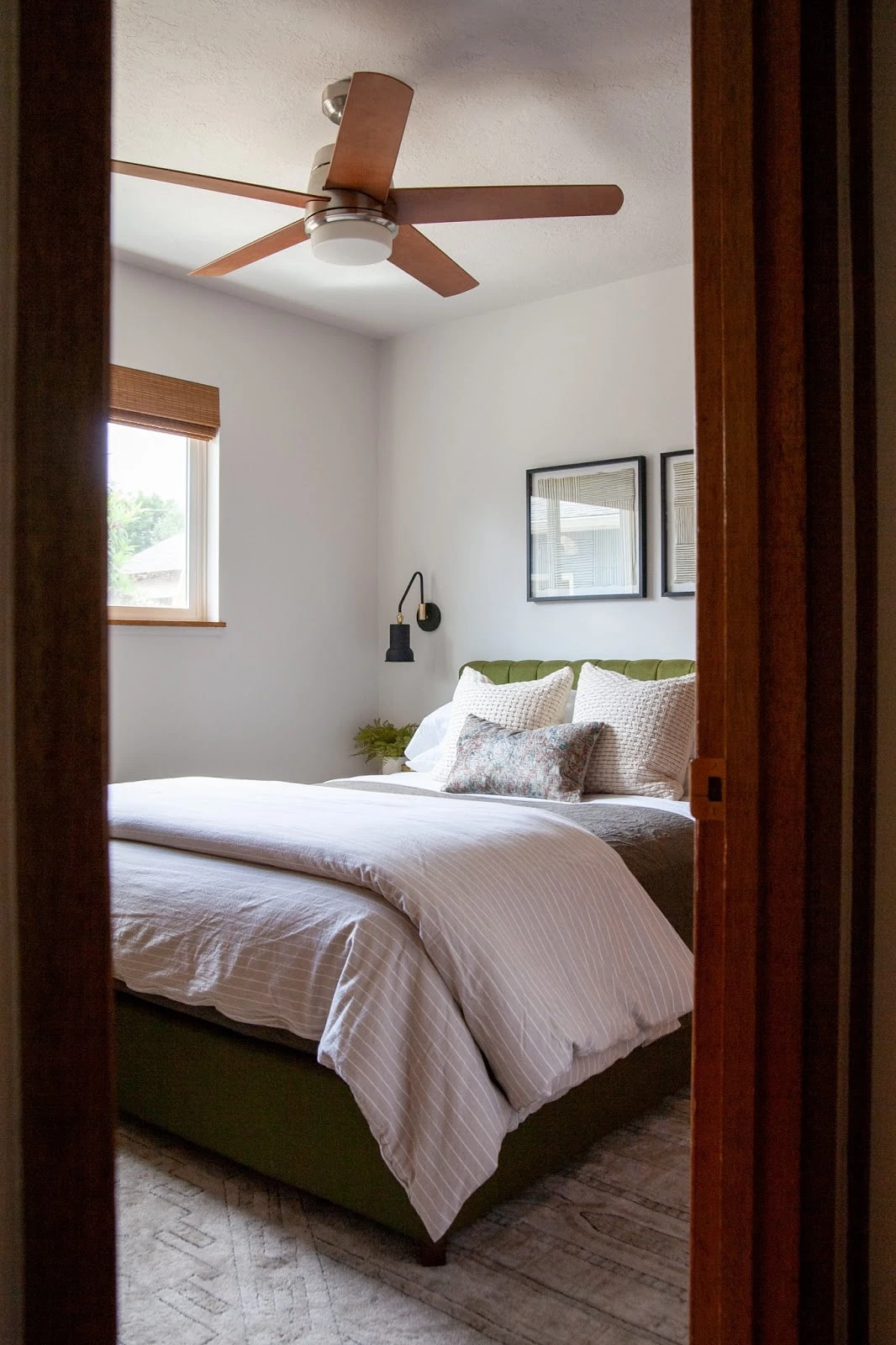 Guest room with green headboard, neutral bedding and fan