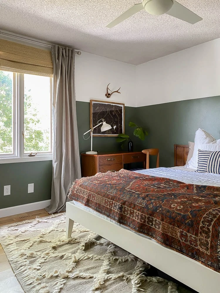 rug wall hanging above desk in a boho bedroom with green and white walls