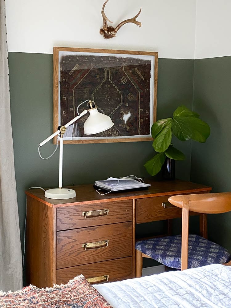 closeup of diy rug framed project hanging over vintage desk with a task light in front