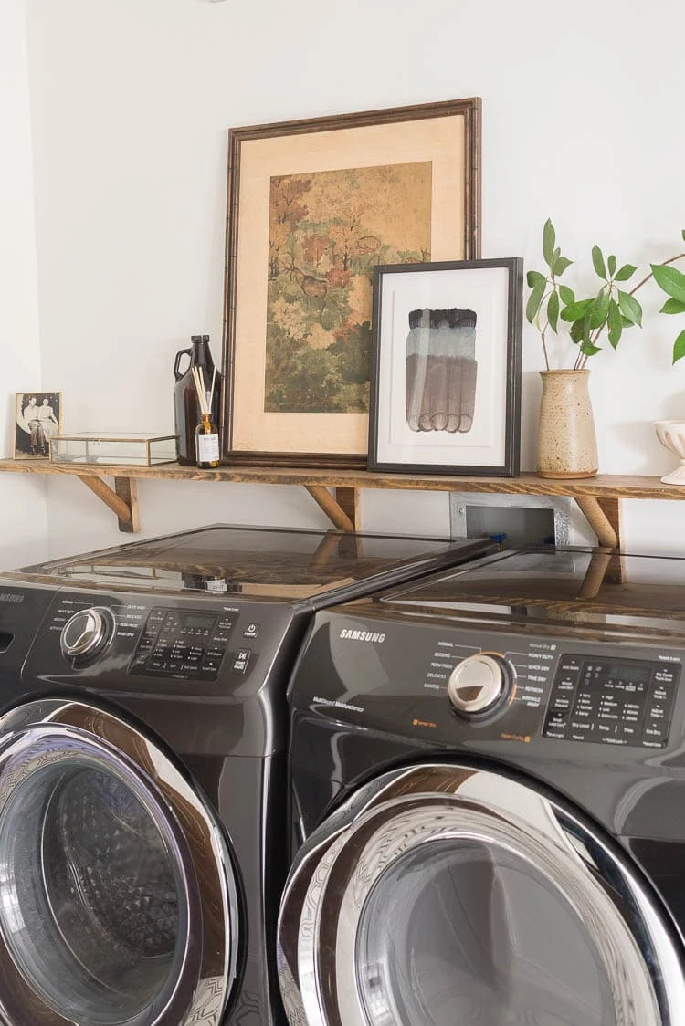 home decor challenge featuring a deer painting on a shelf above a washer and dryer in the laundry room 