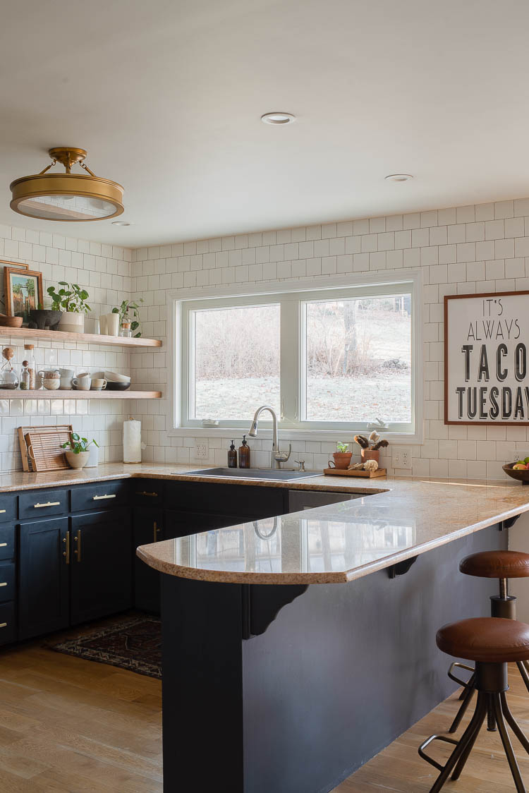 enlarge window in the kitchen showing window above kitchen sink with dark cabinets and subway tile