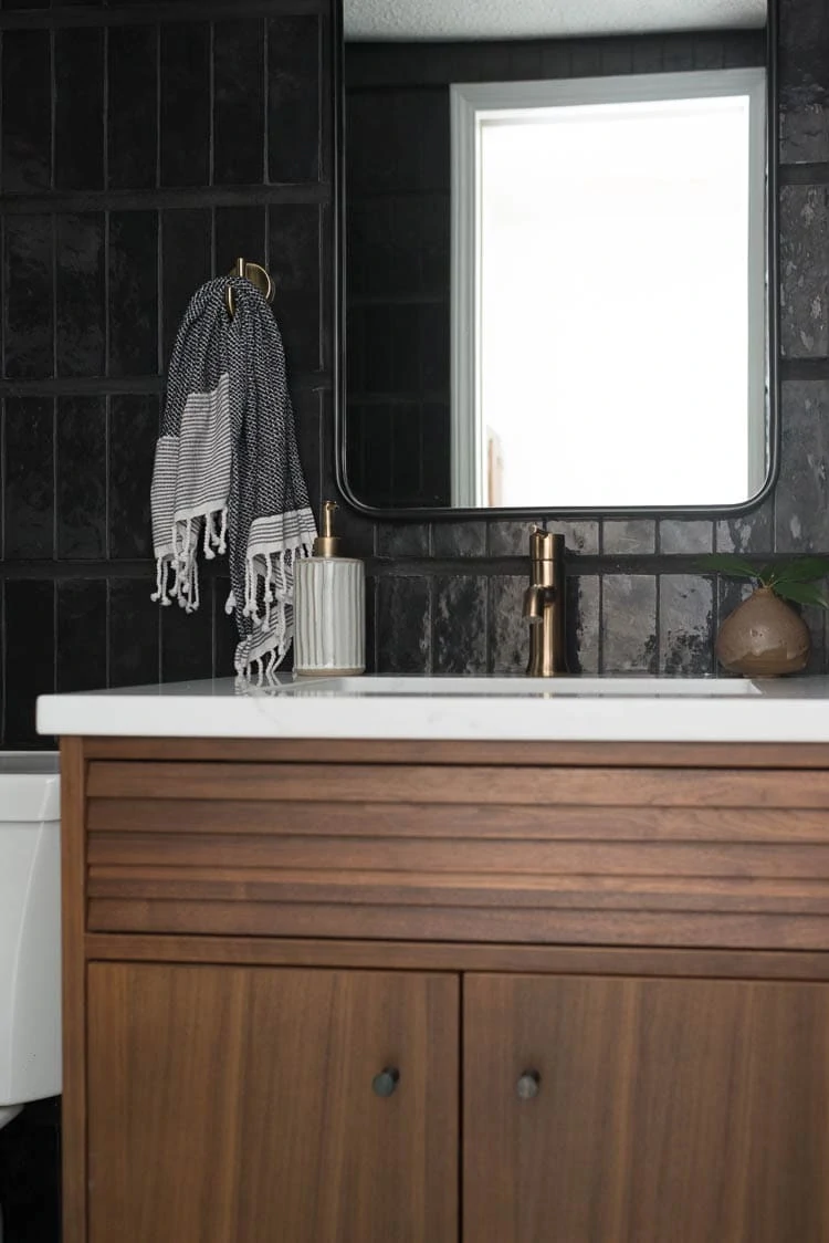 Use an epoxy adhesive to attach sink clips on a vanity top. Showing a closeup photo of walnut vanity with white quartz and brass fixtures. 