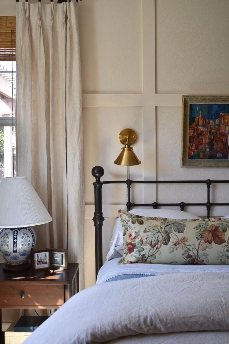 millwork in bedroom with iron bed and floral pillow