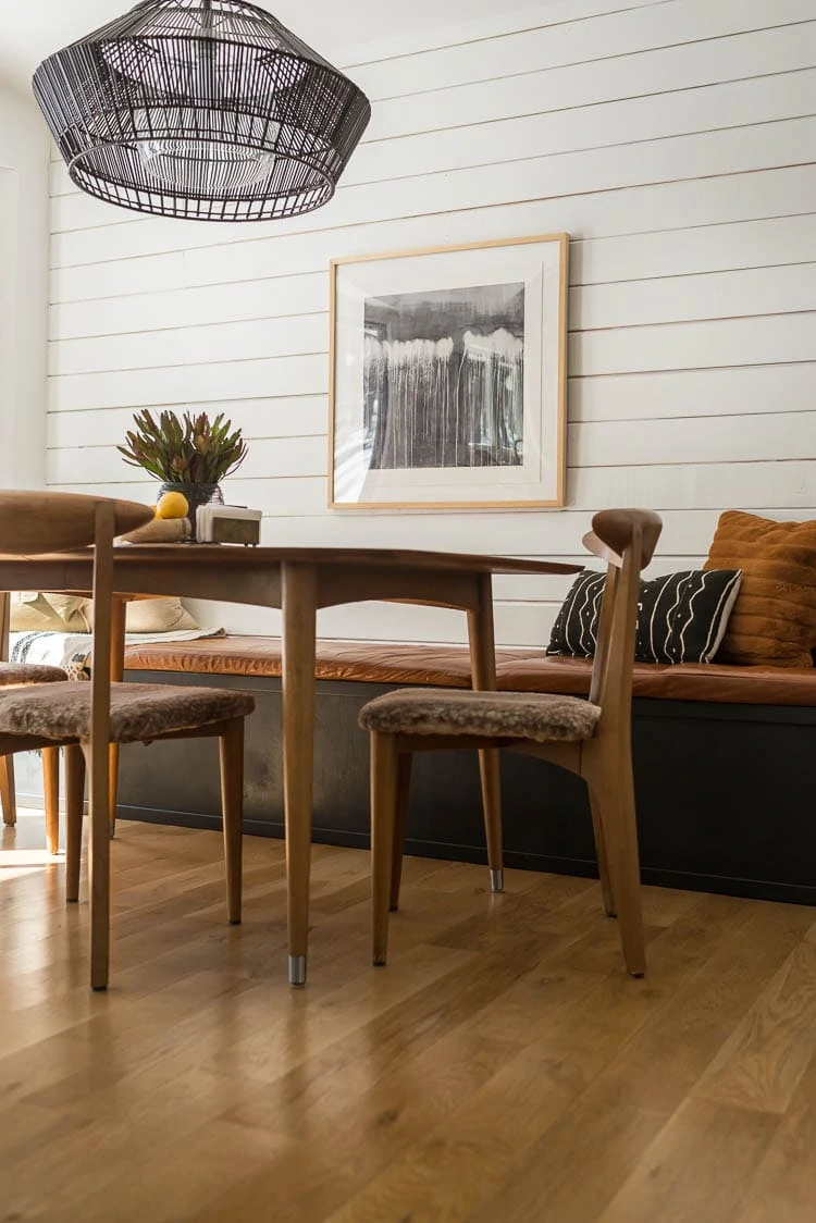 Black dining bench built in with wood table and shiplap walls. 