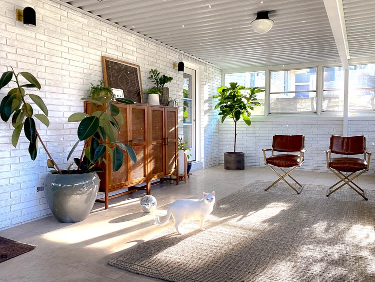 Brick sunroom with lots of windows and details on the sunroom furniture and decor. 