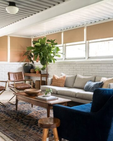 Four seasons sunroom with a vintage rug, grey couch and plants