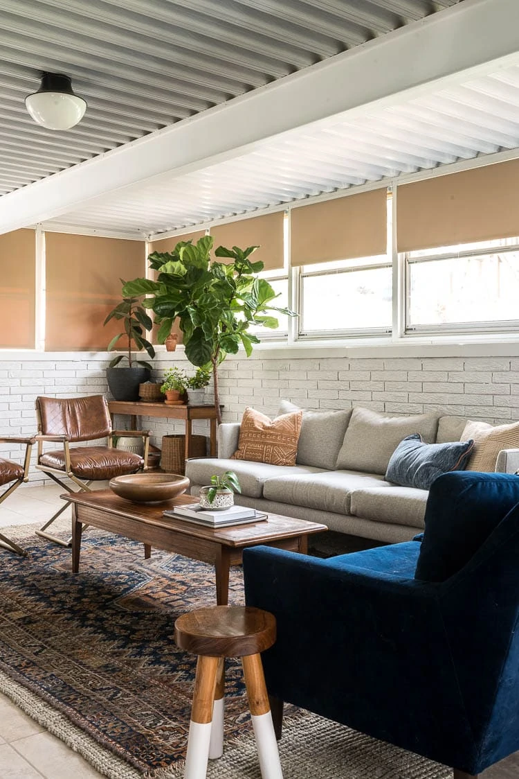 Four seasons sunroom with a vintage rug, grey couch and plants