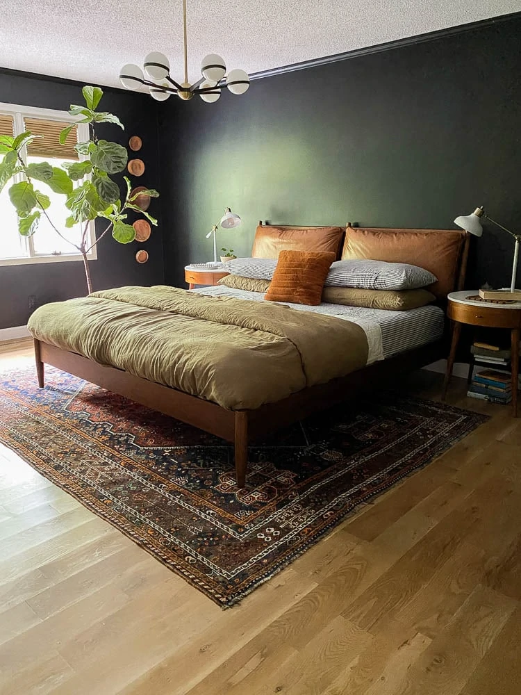 Linen sheets in the bedroom with a vintage rug and midcentury bed. 