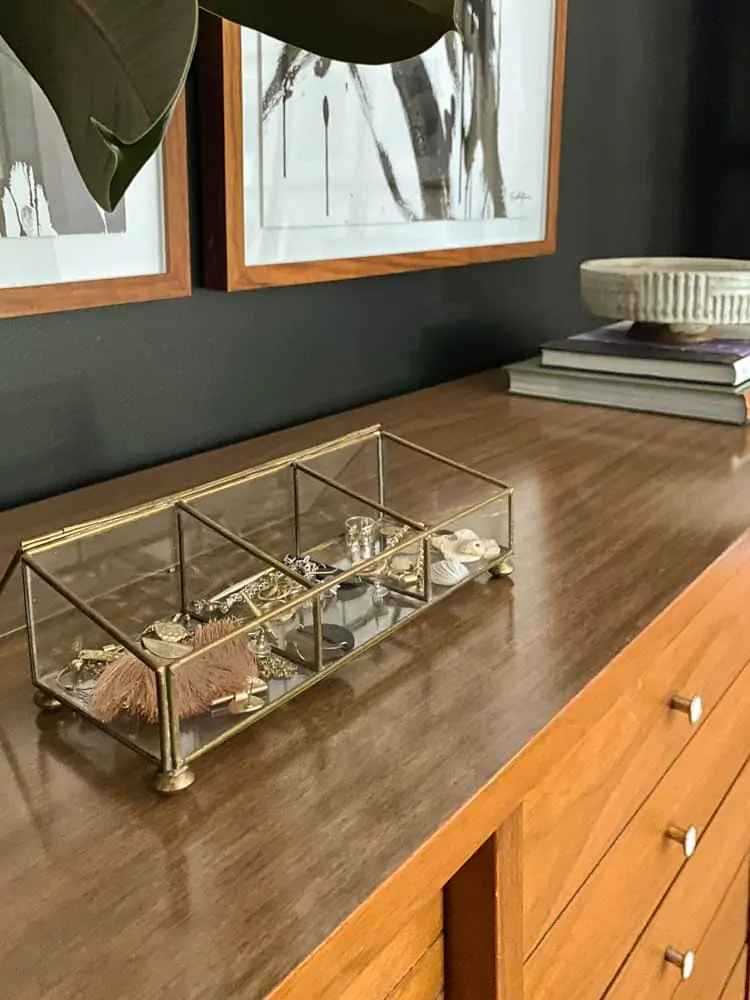 brass and glass jewelry organizer on midcentury dresser in bedroom