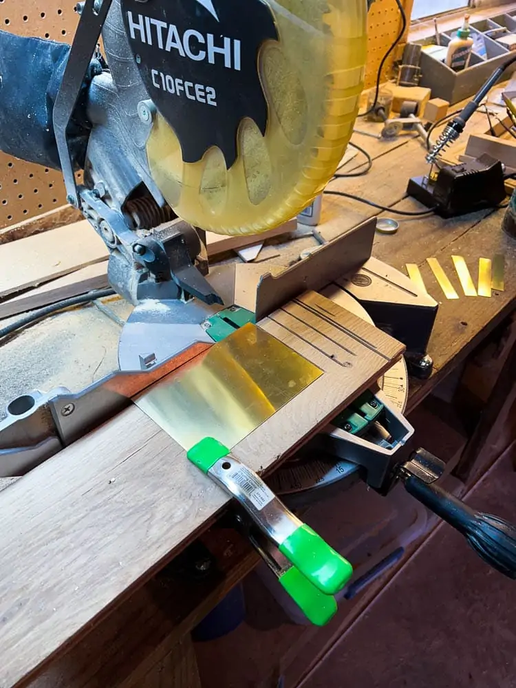 clamping craft sheet metal onto a scrap board and cutting it with a miter saw