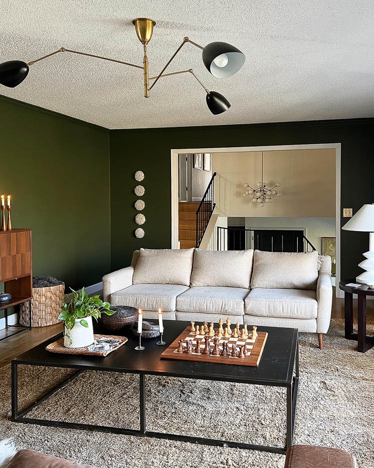 Green living room with tan couch and brass wall switch plate