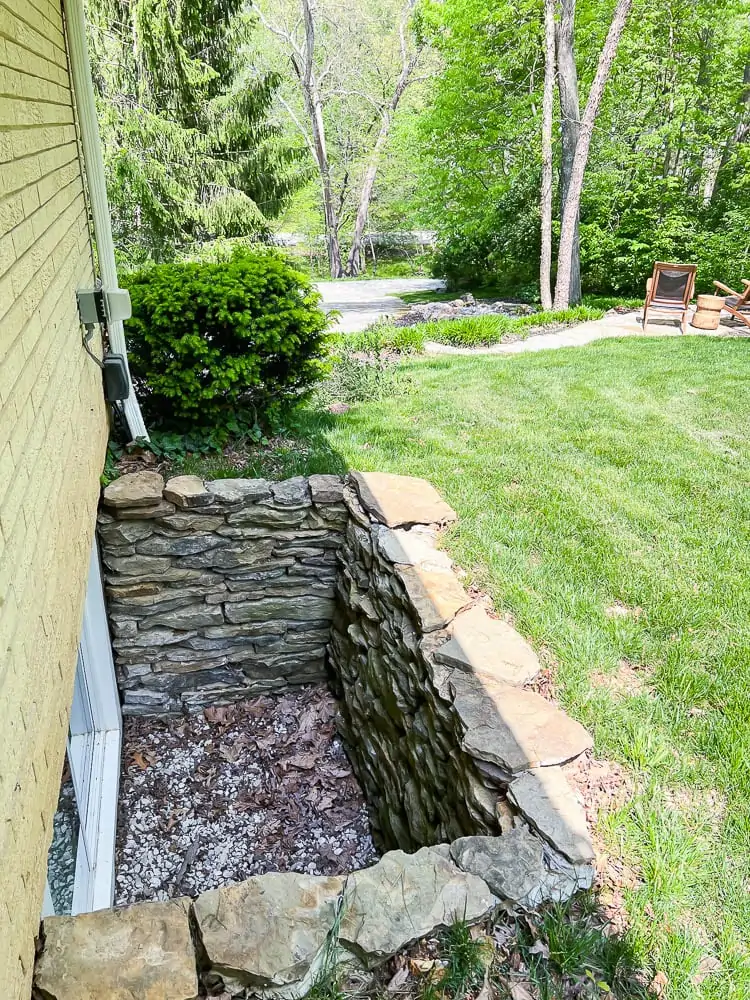 stacked stone outside with French drain under by basement window