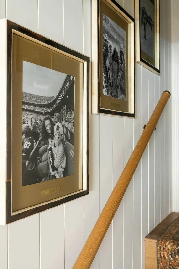 Customizing wall frames by painting mat board and engraving brass tags for photo frames showing a picture of frame on shiplap over stairs 