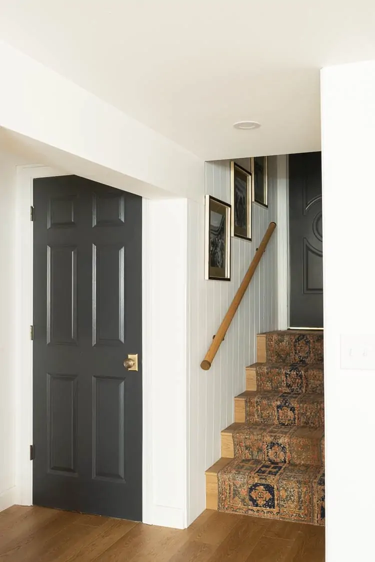 Basement Stairs featuring a Persian rug on the stairs, shiplap in the basement and a gallery wall on the stairwell 