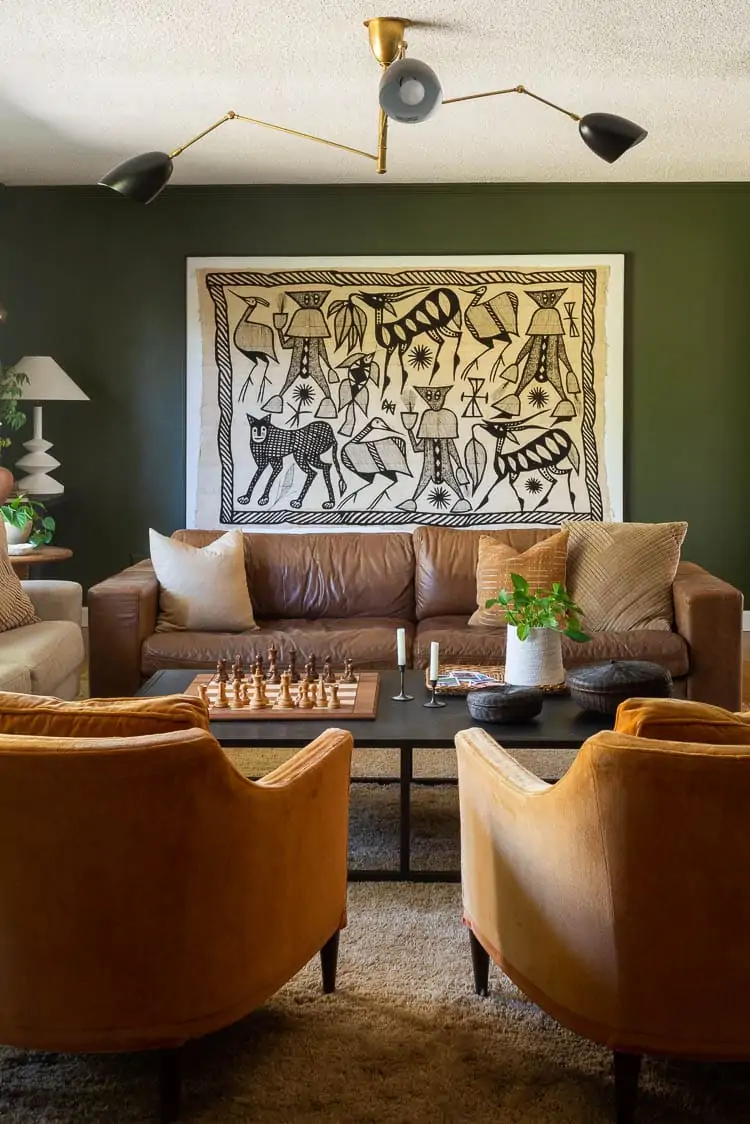 green living room walls with leather sofa and midcentury orange chairs 