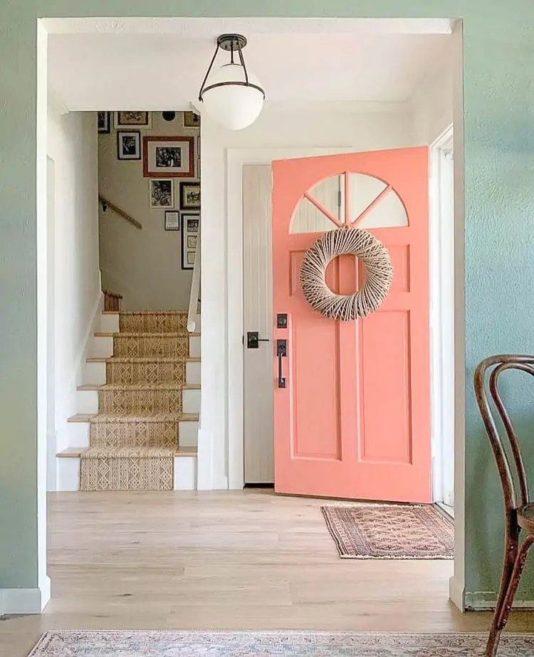 coral front door with indoor outdoor rug on stairs 