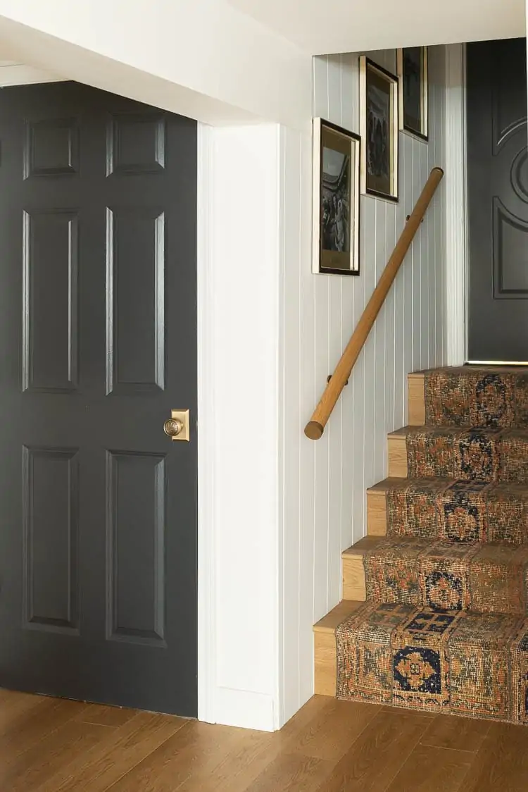 basement stairs with rug runner over stairs, gallery wall on stairs and a wooden handrail DIY project