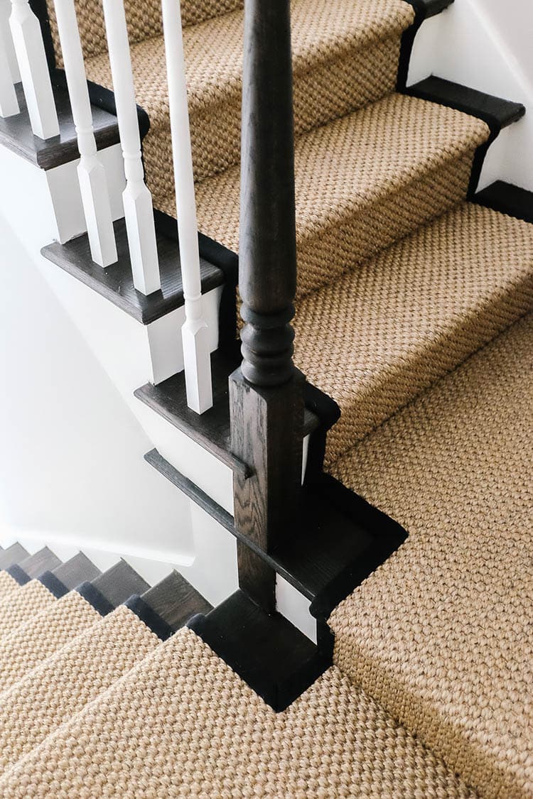 Closeup of brown sisal carpet with black border on stair treads 