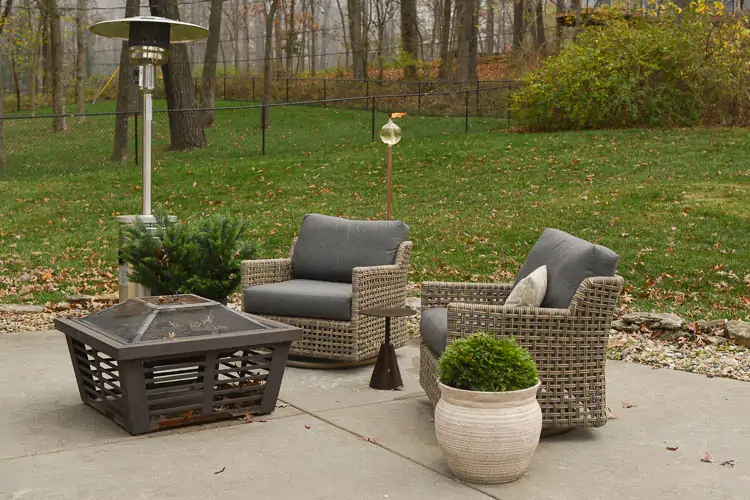 back patio with river rock showing woven arm chairs, outdoor heater and fire pit 