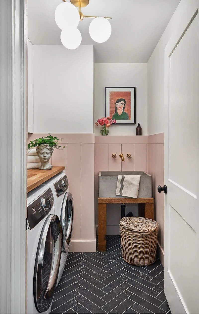 pink half shiplap wall in laundry room with black herringbone tile 